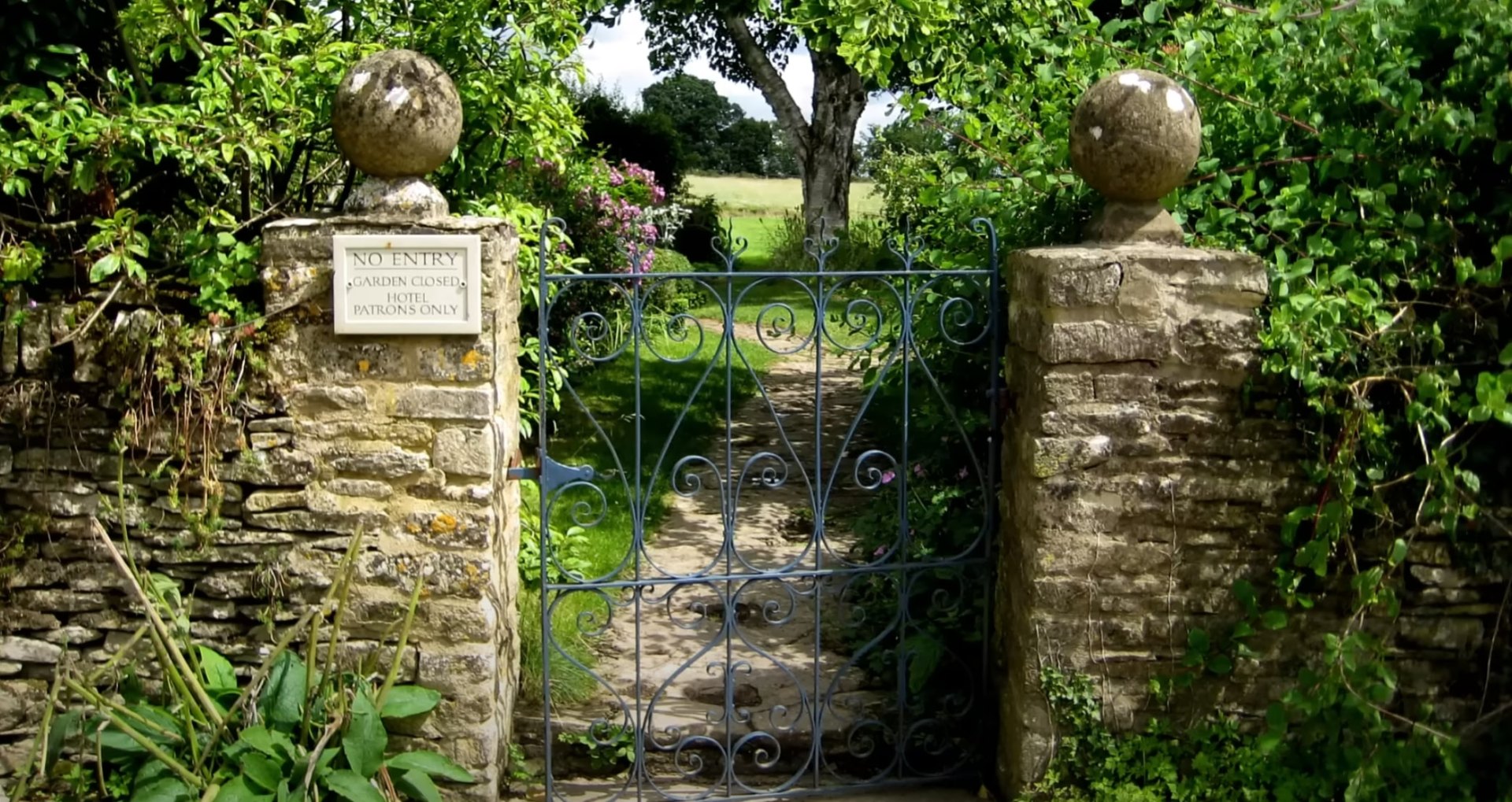 Stone Hardscaping & Garden Entrance Traditional stone garden entrance with decorative wrought iron gate and mature landscaping creating an elegant property entrance