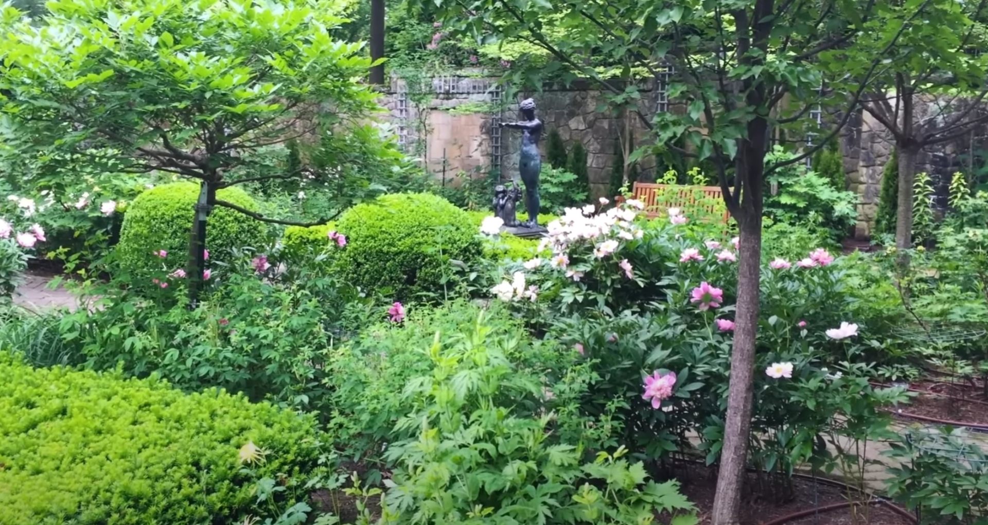 Garden paradise featuring colorful perennial plantings and decorative water feature Lush garden with blooming flowers, sculptural fountain, and well-maintained lawn areas